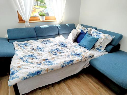 a bed in a room with a blue couch at Kasztanowe zacisze in Połczyno