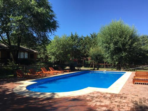 una piscina con sedie e una casa di Cabañas Los Maderos a Villa General Belgrano