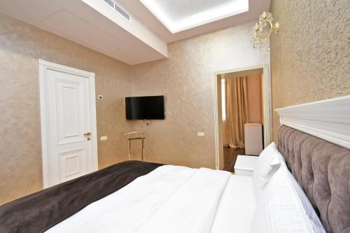 a bedroom with a bed and a flat screen tv at Macao Hotel in Yerevan