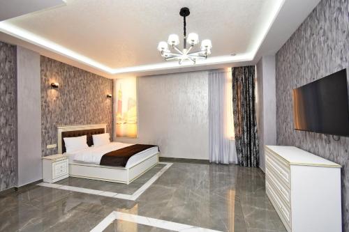 a bedroom with a bed and a television and a chandelier at Macao Hotel in Yerevan