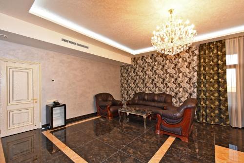 a living room with leather furniture and a chandelier at Macao Hotel in Yerevan