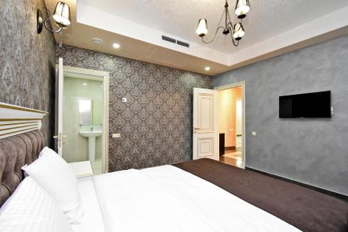 a bedroom with a bed and a flat screen tv at Macao Hotel in Yerevan