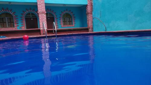 une piscine avec un ballon rouge devant un bâtiment bleu dans l'établissement Hotel Villa Luz, à Puerto Escondido