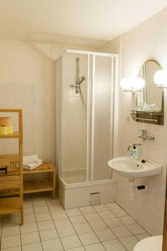 a white bathroom with a shower and a sink at Pension Marie in Český Krumlov