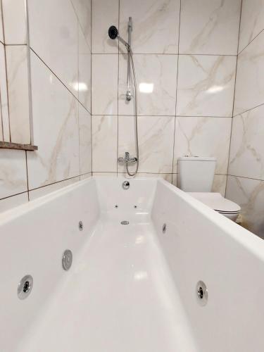 a white bath tub in a bathroom with a toilet at Agros Green Valley Suites in Limassol