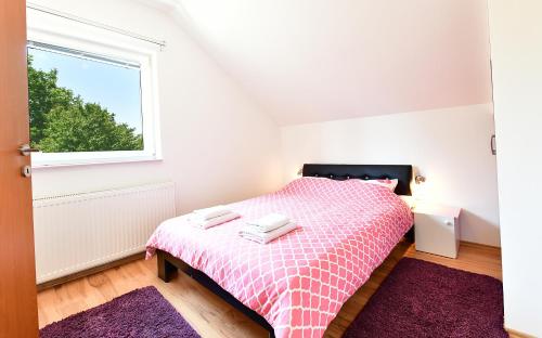 a bedroom with a pink bed with a window at Apartment Anna Maria in Rakovica