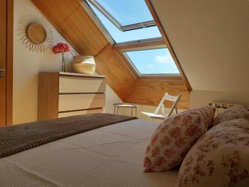 um quarto com uma cama e uma clarabóia em Atico con terraza y piscina comunitaria em Ribadeo