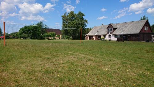 ein großes Feld mit einem Haus und einer Scheune in der Unterkunft Pirmie Zaļmeži in Jūrkalne