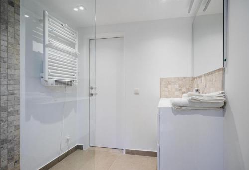 a white bathroom with a shower and a refrigerator at Le Cottage du Raidillon in Malmedy