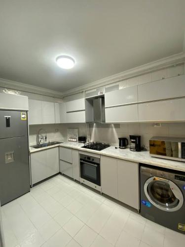 cocina con armarios blancos, lavadora y secadora en Luxury 3 bedroom Apartment with a great Seaview en Alexandría