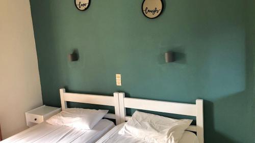 um quarto com duas camas e dois relógios na parede em Neos Alexandros by Go4sea em Kato Korakiana