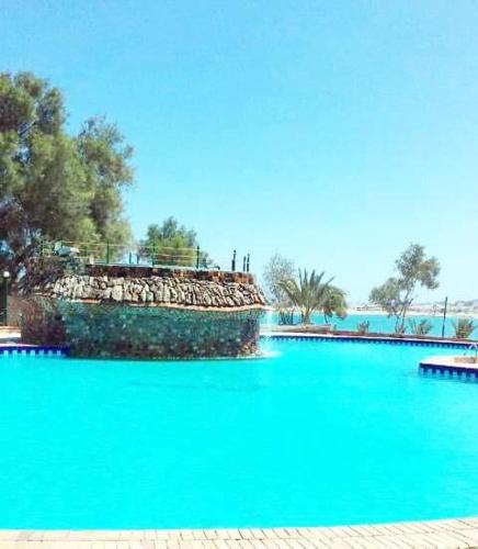 a large pool of blue water with trees in the background at شاليه رائع مجدد للعائلات فقط باندلسيه مطروح in Marsa Matruh