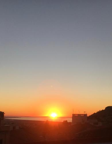 a sunset over a city with the sun in the sky at B&B SHARDANA in Sennori