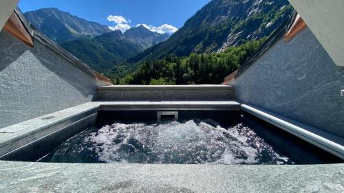 a pool of water with mountains in the background at Gran Baita Hotel & Wellness in Courmayeur