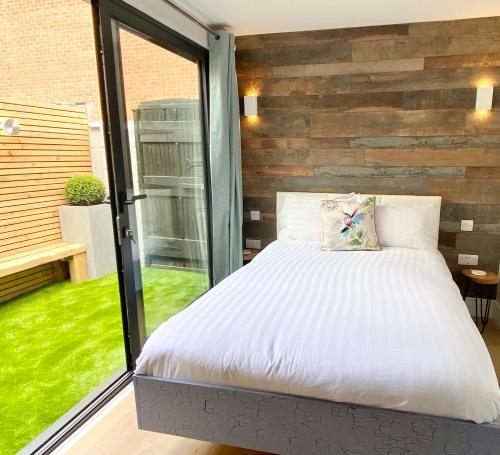 a bedroom with a bed and a large window at Coastline Retreats - Cloud9 Holiday Accommodation- 2 Bedroom self contained garden flat - Luxury bath, Netflix, Superfast Wifi, Parking included in Bournemouth
