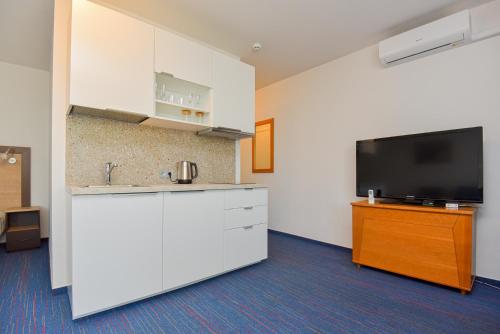 an empty room with a flat screen tv and a kitchen at Apartamentai Palangos centre in Palanga