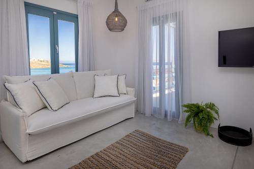 Royal-Ma Resort في Perástra: غرفة معيشة بيضاء مع أريكة بيضاء وتلفزيون