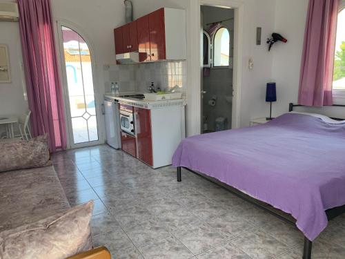 a bedroom with a purple bed and a kitchen at 7Syn7 in Oreoí