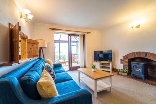 a living room with a blue couch and a fireplace at Morea Cottage - 2 Bed in Horning