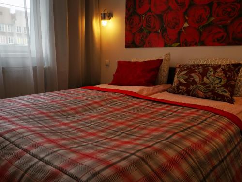 a bedroom with a bed with a plaid blanket at Apartament Ogarna II in Gdańsk