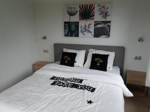 a bedroom with a white bed with black pillows at Luxe bungalow op rustig vakantiepark. in Dronrijp