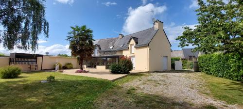 une grande maison blanche avec un palmier dans la cour dans l'établissement Villa Excallibur, aux portes de Brocéliande, à Carentoir
