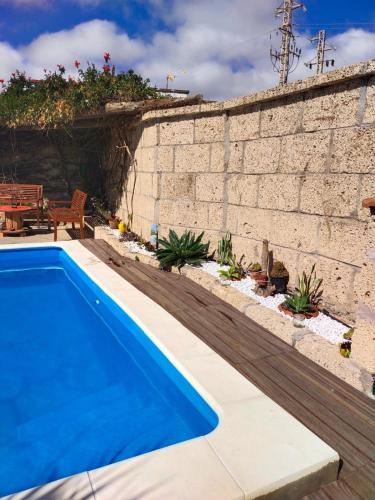 a blue swimming pool next to a brick wall at Villa los gavilanes in Santa Cruz de Tenerife