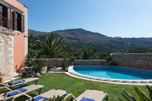 una piscina en un patio con sillas y una casa en Venetico Palazzo, en Khromonastírion