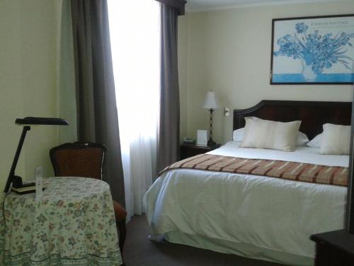 a hotel room with a bed and a table and a window at Hotel Chagall in Copiapó