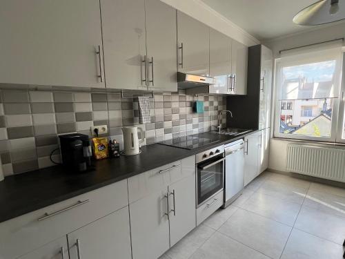 a kitchen with white cabinets and a large window at Apartment - Place Jourdan & EU institutions in Brussels