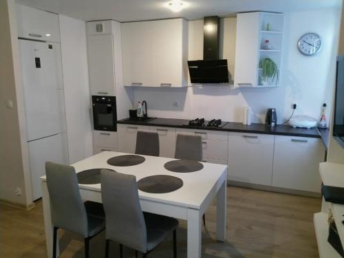 a white kitchen with a white table and chairs at Apartament Blisko Plaży in Gdańsk