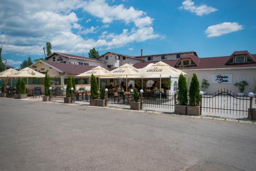 a restaurant with white umbrellas in front of a building at Seva Hotel Health Club in Campina