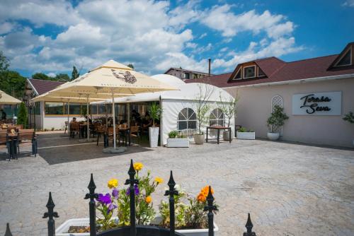 a patio at a restaurant with an umbrella and flowers at Seva Hotel Health Club in Campina