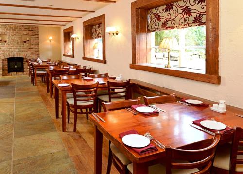 a restaurant with wooden tables and chairs and a fireplace at The View at the White Horse Woolley Moor in Clay Cross