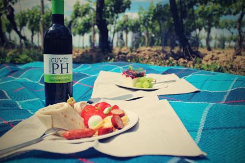 a bottle of wine and a plate of fruit on a table at Vinařský penzion Přední Hora in Velké Bílovice