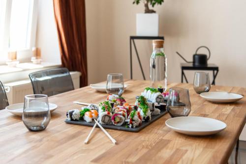 a wooden table with a plate of sushi and wine glasses at Kaßberg - Studio mit Balkon, Netlfix und Wifi in Chemnitz