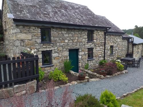 uma casa de pedra com uma porta verde e algumas plantas em St Mullins Camping em Saint Mullins