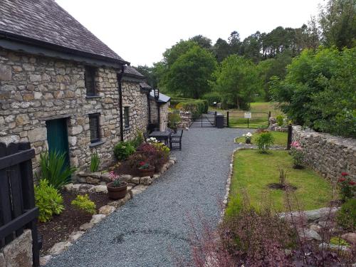 un edificio in pietra con un sentiero che conduce a un giardino di St Mullins Camping a Saint Mullins