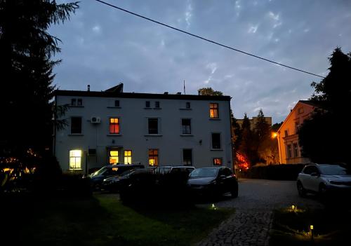 a white building with lights on in a parking lot at Hotel i Restauracja Castle in Bystrzyca Kłodzka