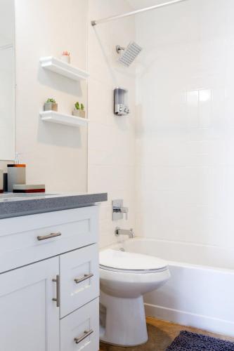 a white bathroom with a toilet and a bath tub at LaRocco On Turney Biltmore in Phoenix