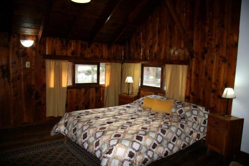 a bedroom with a bed in a room with wooden walls at La Avutarda in San Carlos de Bariloche