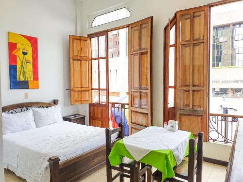 a bedroom with a bed and a table and windows at Hotel Colonial Manizales in Manizales