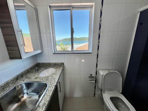 ein Bad mit einem Waschbecken, einem WC und einem Fenster in der Unterkunft Acorde Com o Cenário Beira Mar - Coberturinha in Bombinhas