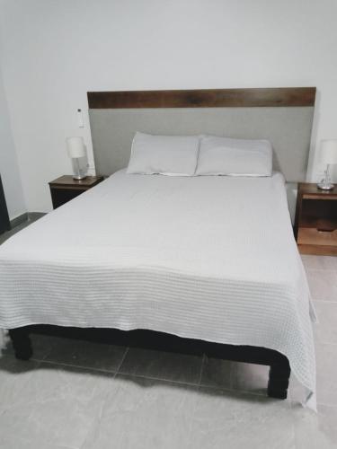 a bedroom with a large white bed with two night stands at Consulado Americano a 5 minutos D3 in Ciudad Juárez
