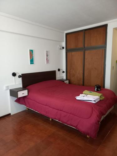 - une chambre avec un lit rouge et une porte en bois dans l'établissement Orillas del Nahuel, à San Carlos de Bariloche