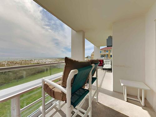 a chair on a balcony with a view of the ocean at Regency Towers #205 West in Pensacola Beach
