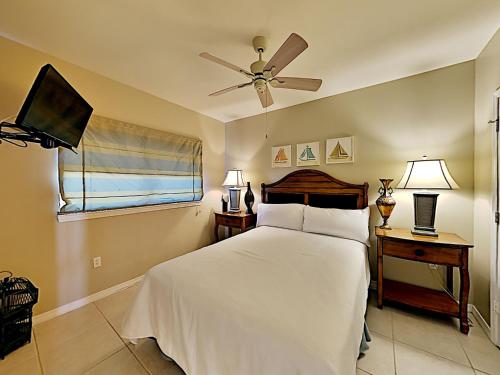 1 dormitorio con 1 cama con ventilador de techo y TV en Emerald Isle #806, en Pensacola Beach