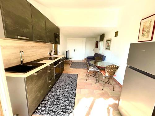 Il comprend une cuisine équipée d'un réfrigérateur et d'une table avec des chaises. dans l'établissement Plein ciel, à Saint-Raphaël