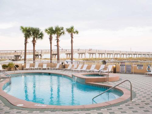 a swimming pool with palm trees and a beach at Summerwinds #204 in Navarre