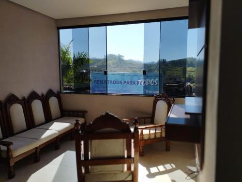 a room with a large window with chairs and a table at Canastra Flat Hospedagem in Vargem Bonita